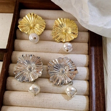 Detail of baroque pearl earrings with golden and silver metallic petal design