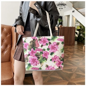 Detail of canvas tote bag featuring vibrant pink hibiscus print and white rope handles