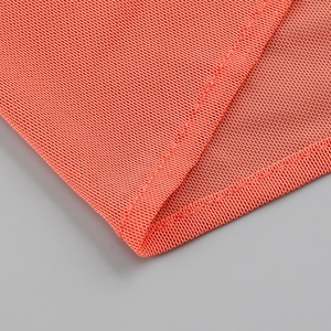 Macro shot of orange mesh fabric texture and stitching details for the dress