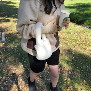 Detail of warm brown knit gloves and white fluffy handbag in an autumn outdoor setting