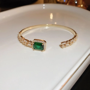 Macro shot of an adjustable emerald green square zircon bracelet on a white ceramic tray