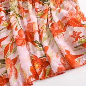 Close-up of floral chiffon fabric with orange lily print and neat overlock stitching