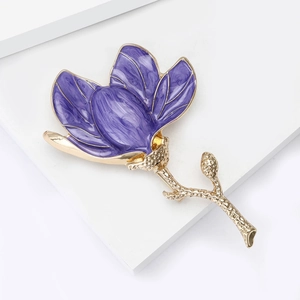 Detailed view of purple enamel magnolia flower brooch with golden textured petals