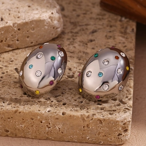 Detail of silver oval earrings with colorful zircon stones on a textured stone base