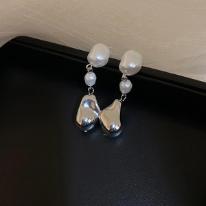 Gros plan de boucles d'oreilles perles baroques et métal argenté sur fond noir élégant