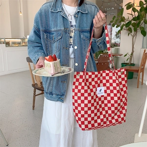 Red and white checkered canvas tote bag with You need this one label held by a model