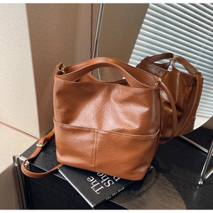 Detail of brown PU leather tote bag with pleated texture and adjustable strap