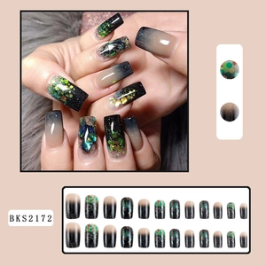 Long coffin false nails featuring black to nude gradient with green glitter and foil flakes