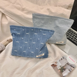 Detailed view of denim bow makeup bags in dark and light blue with heart embroidery