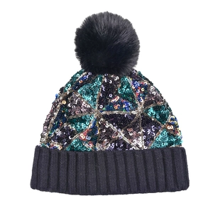 Dettaglio delle cuciture in paillettes e pompon soffice sul berretto in maglia nera