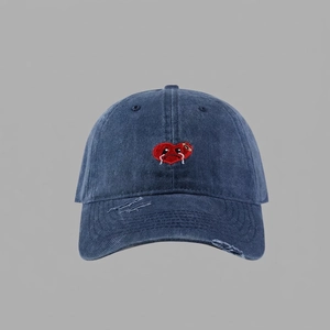 Close-up of red crying heart embroidery and distressed denim details on baseball cap