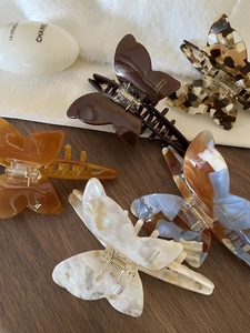 Close-up of butterfly claw clips in amber and tortoiseshell on a wooden surface
