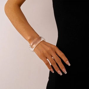 Nahaufnahme eines klaren Acryl-Armreifs am Handgelenk eines Models in Schwarz