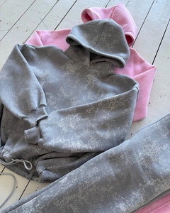 Ensemble sweat à capuche gris délavé et sweat rose sur un sol en bois blanc