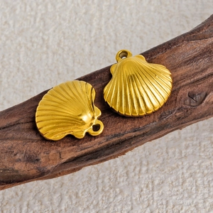 Two golden stainless steel shell pendants for DIY jewelry making on wooden background