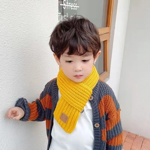 Detail of yellow knitted kids scarf with brown EST LOVE leather patch for winter