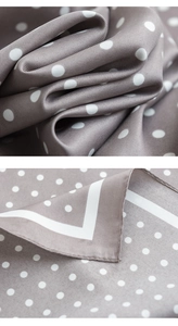 Detailed view of grey silk scarf with white polka dots showing twill texture and rolled edges