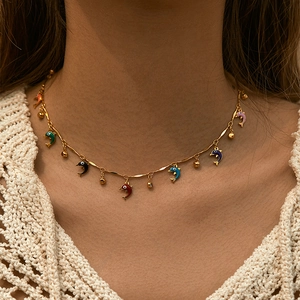 Detail of bohemian gold-plated choker necklace with colorful dolphin charms on a model