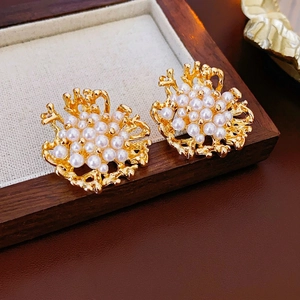 Orecchini vintage in corallo dorato con perle su vassoio in legno e lino