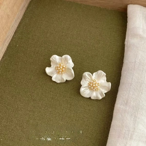 Close-up of camellia earrings with creamy beige petals and sparkling crystal center