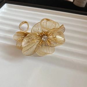 Close-up of golden hollow flower bangle with sparkling rhinestone on white textured tray