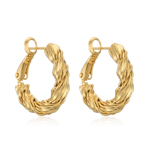 Detailed macro view of twisted gold C-shaped hoop earrings with metallic glossy finish
