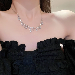 Close-up of silver branch necklace with light blue teardrop crystal on model neck