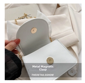 White textured crossbody bag with bow detail, gold chain strap and magnetic snap closure.