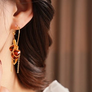 Detailed close-up of 18K gold plated heart earrings with amber glass drop and tassels