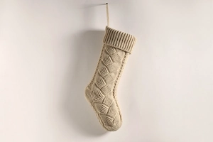 Detail of beige cable-knit Christmas stocking showing woven texture and hanging loop