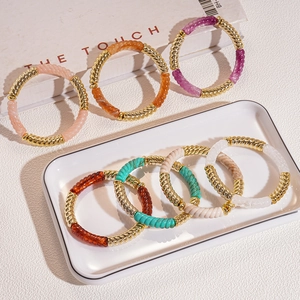 Bracelets en perles acryliques avec spirales dorées présentés sur une table blanche épurée