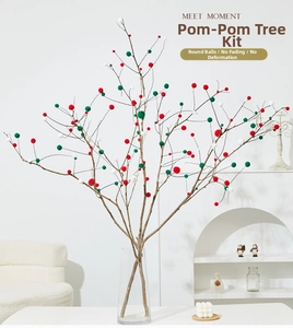 DIY Christmas tree kit with red green and white pom poms on natural branches in a modern room