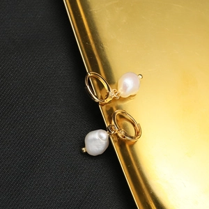 Baroque natural pearl drop earrings with elegant golden hoops on a luxury display