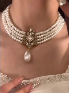Close-up of a four-layer pearl choker with a vintage gold pendant and a teardrop pearl drop