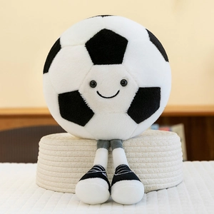 Plush soccer ball character with legs and cute smiley face sitting on a woven mat
