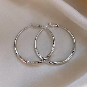 Macro shot of silver twisted hoop earrings with S925 hallmark on silk fabric
