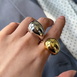 Close-up of minimalist teardrop rings in gold and silver finish worn on fingers