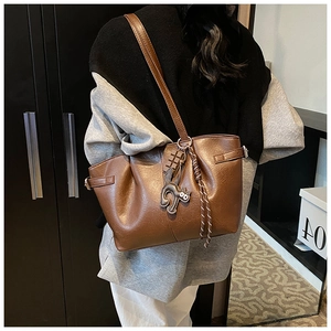 Brown pleated tote bag detail featuring soft leather texture and cute cat charm