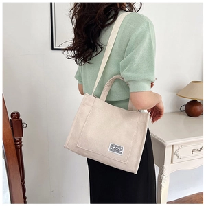 Beige corduroy tote bag shown on shoulder in a bright minimalist room setting