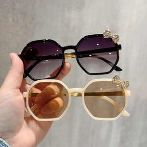 Detail of child sun glasses with rhinestone bow and trendy polygonal gradient lenses