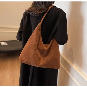 Rear view of model wearing a large brown suede tote bag with minimalist indoor aesthetic