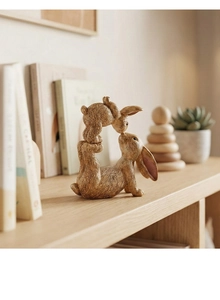 Dettaglio di statuette di conigli in resina con texture realistica e posa genitore-figlio