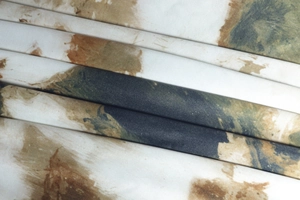Detail of abstract ink print fabric with elegant pleats in olive and caramel tones