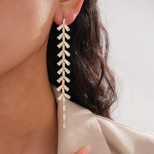 Elegant gold leaf tassel earrings with baguette-cut zircons worn on a female model