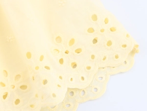 Close-up of yellow embroidered eyelet cotton fabric with scalloped edge detail
