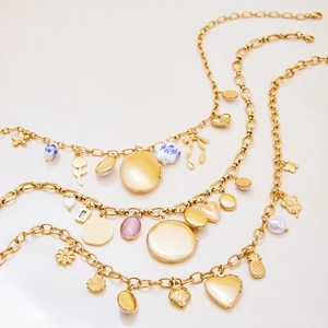 Gros plan du collier doré triple épaisseur avec pendentifs ronds et floraux chic