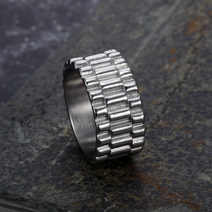 Industrial style silver stainless steel ring with textured gear pattern on stone background