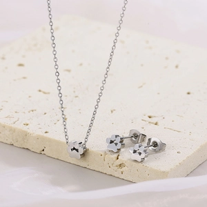 Close-up of silver mesh cat paw necklace and earrings on a textured stone base
