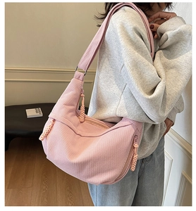 Close-up of pink corduroy crossbody bag with woven rope zipper detail on model