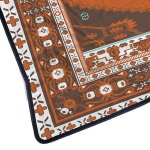 Detail of ethnic pattern flannel blanket with orange accents and reinforced edges